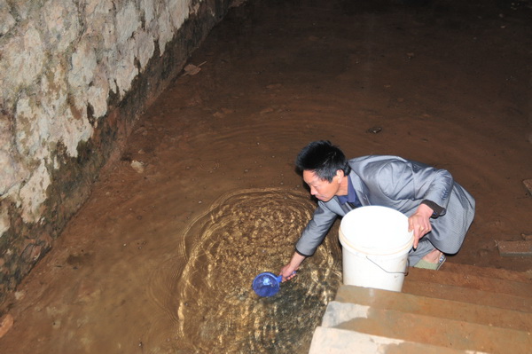 村民在快要干涸的水塘里取水.jpg