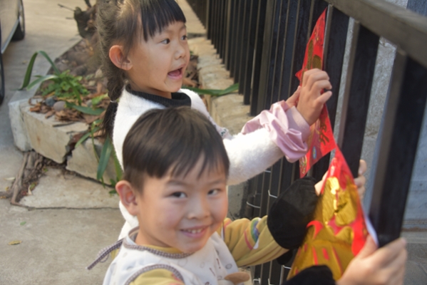 孩子们也像模像样帮忙贴春联、挂门钱。.jpg